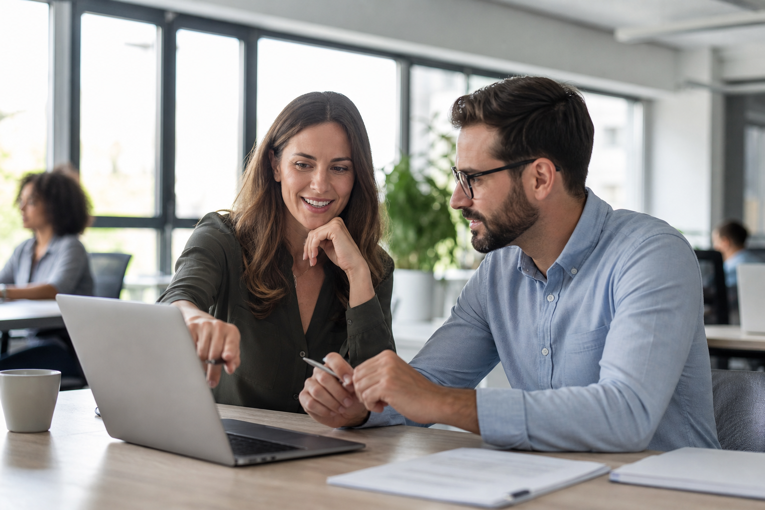 Account executives reviewing pipeline metrics together on a laptop in a bright office